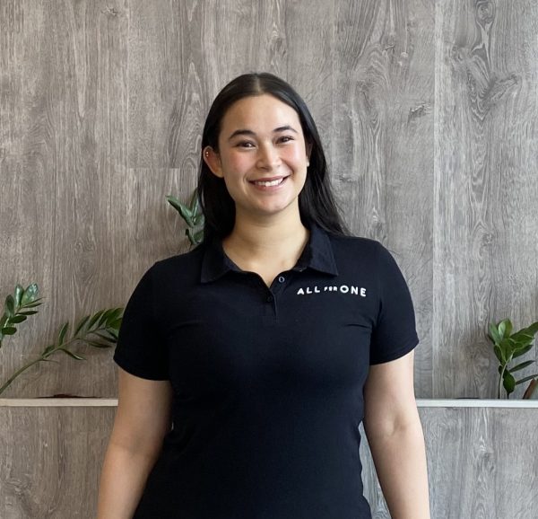 Team member in an All for One polo shirt smiling in the studio foyer