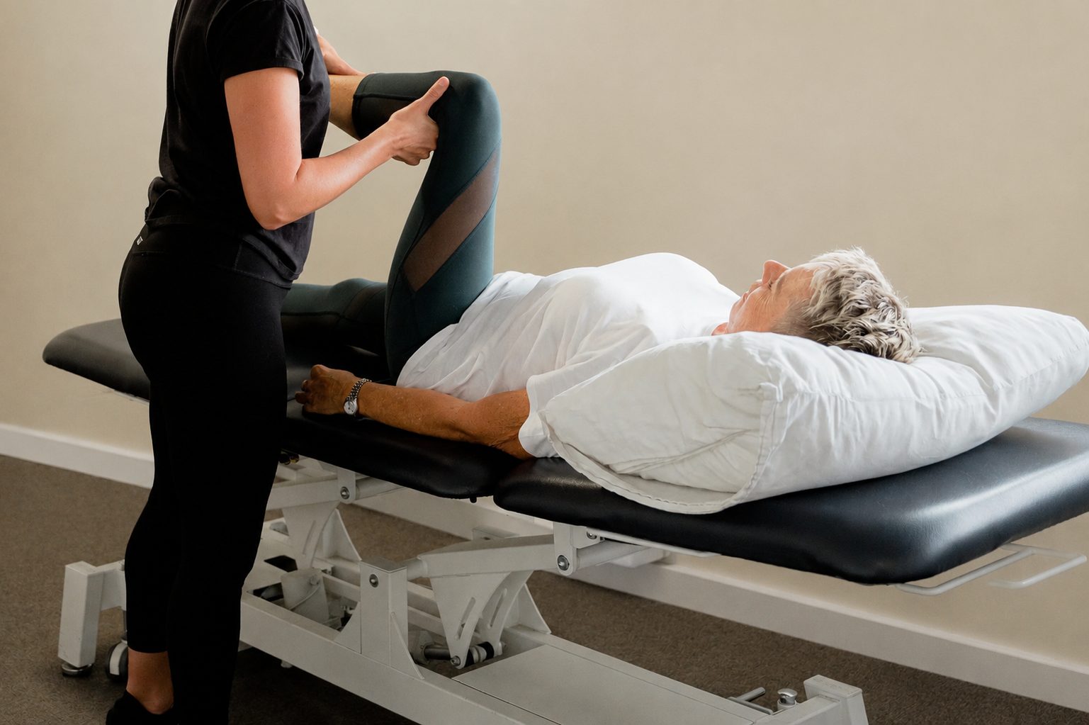 Physiotherapist checking how an older woman's hip moves at All for One