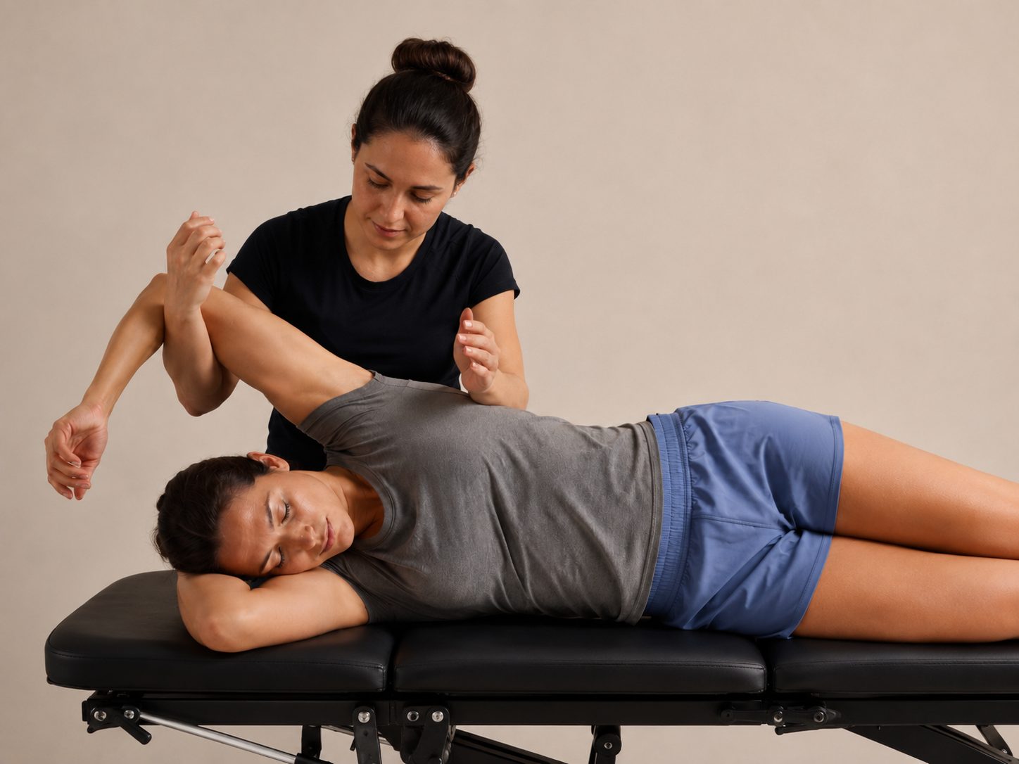 Physiotherapist treating a client&rsquo;s shoulder on a treatment table
