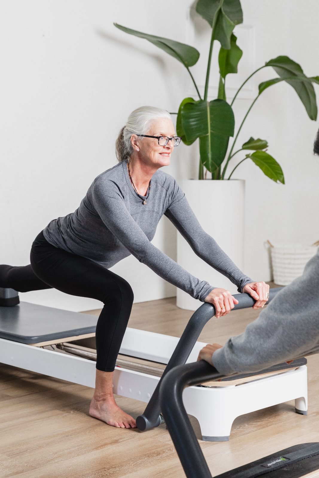 A member mid-exercise in a Reformer Pilates class