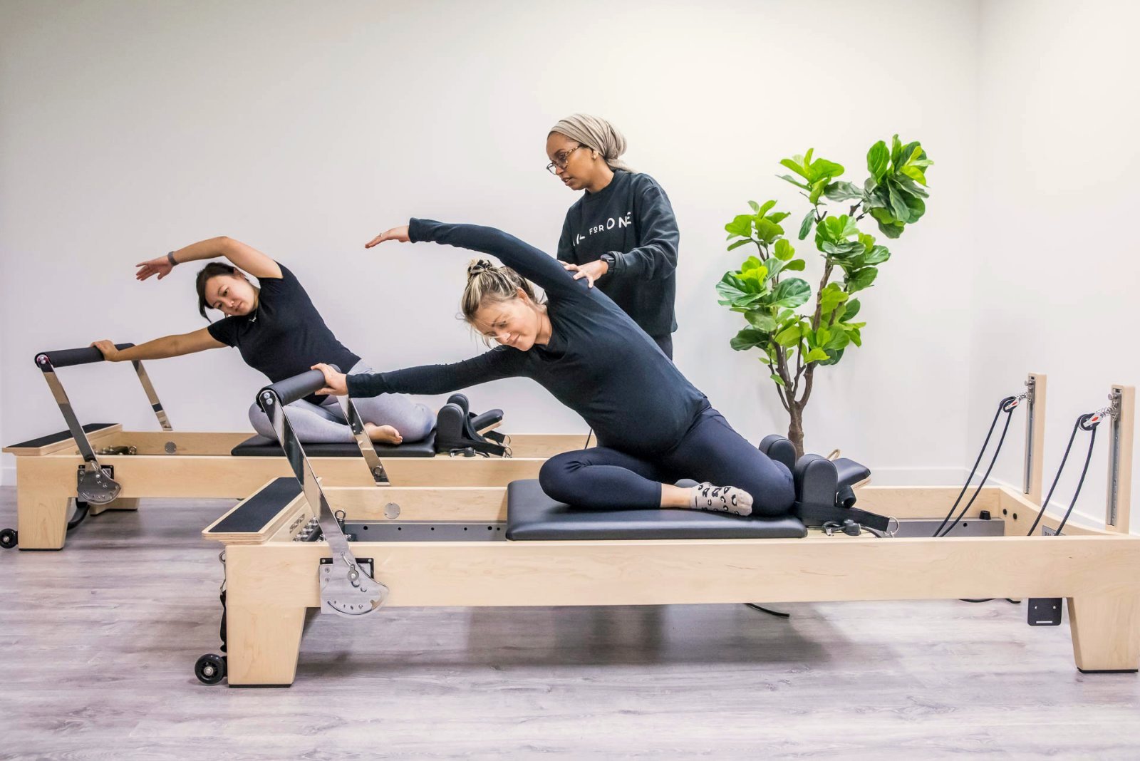 A physiotherapist guiding a pregnant member on the reformer at All for One