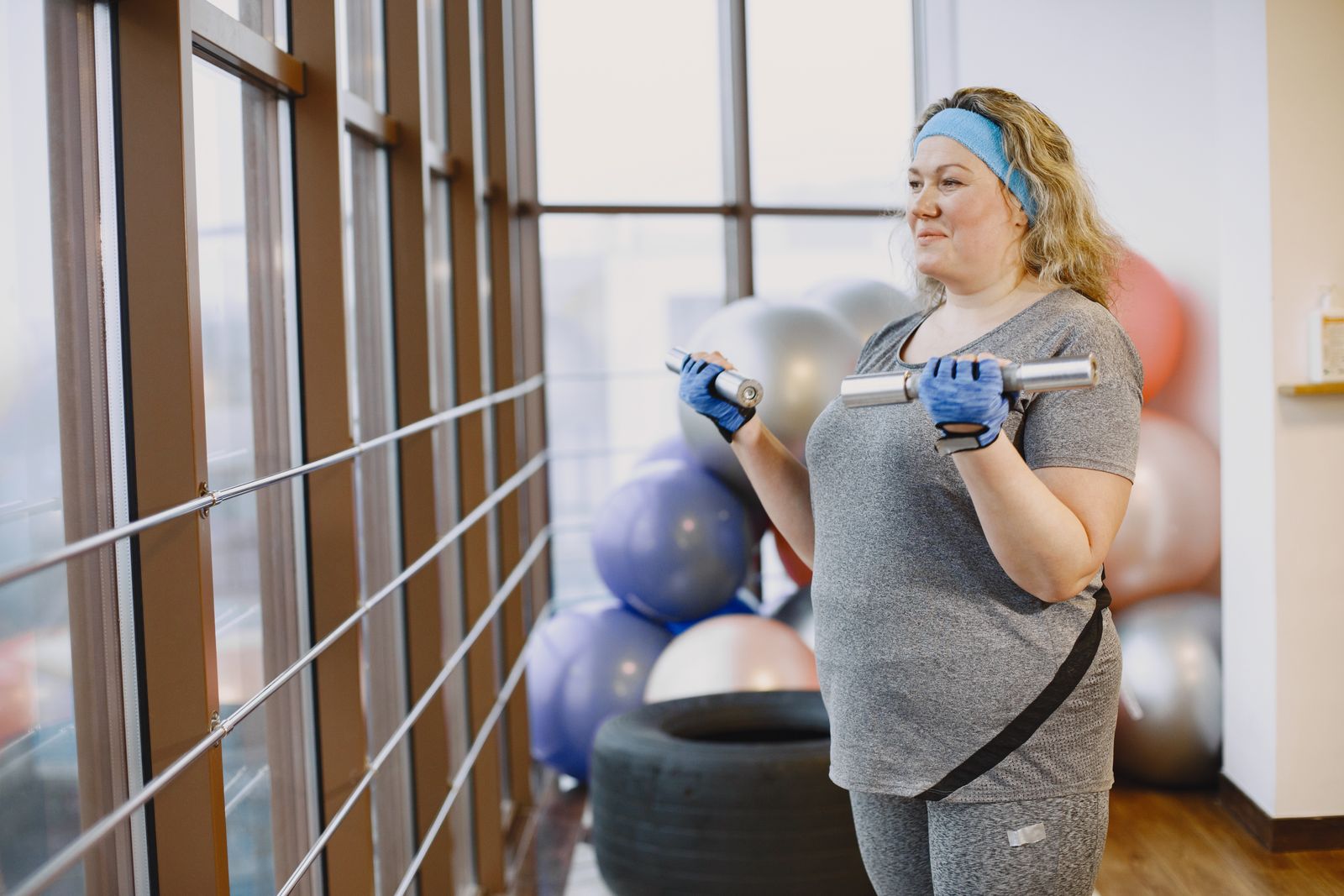 Woman strength training with dumbbells in a bright studio
