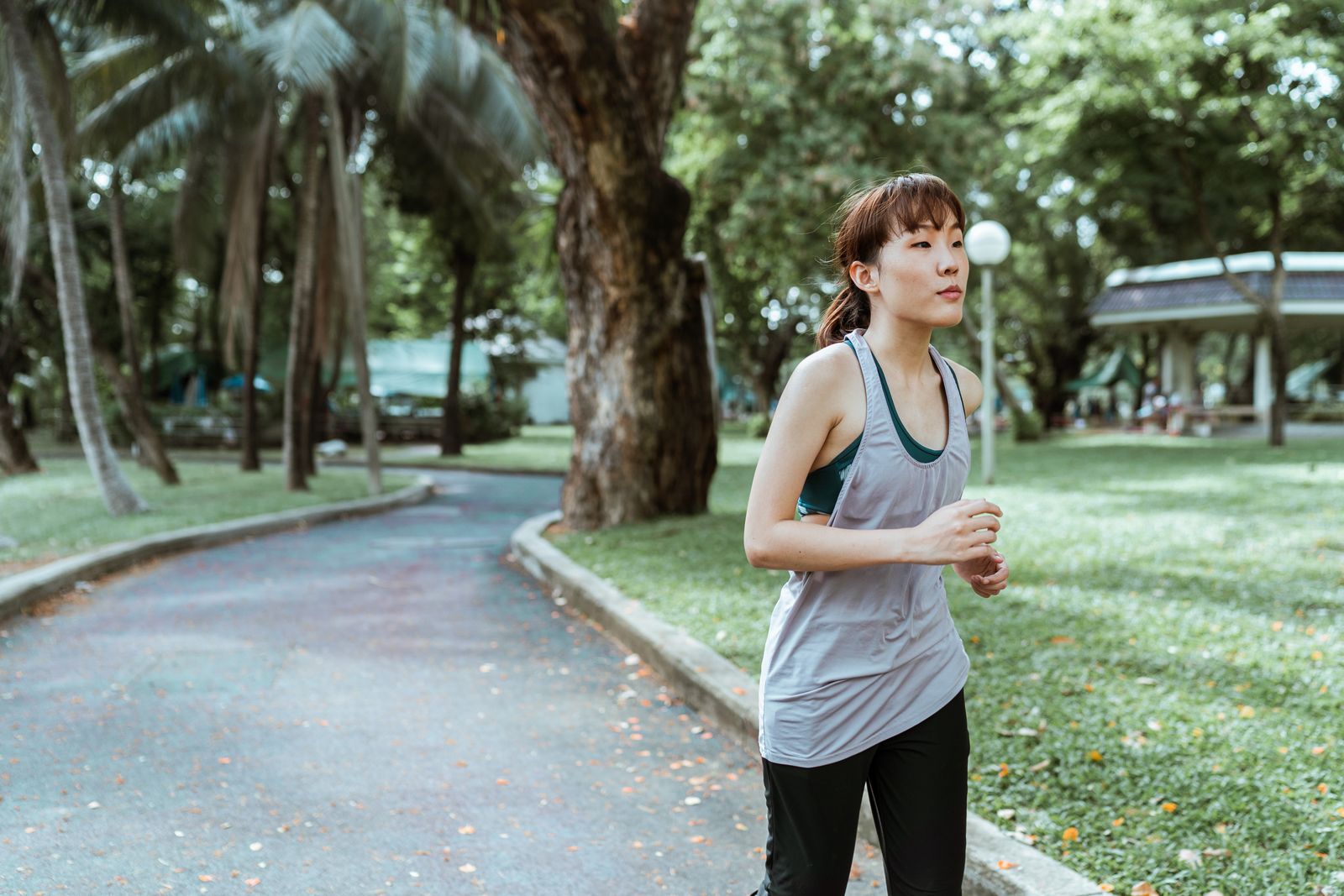 Woman jogging along a path through a green park