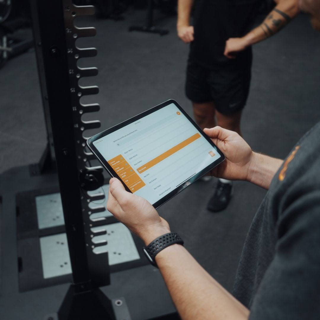 Physiotherapist reviewing VALD strength test results on a tablet beside the force plates