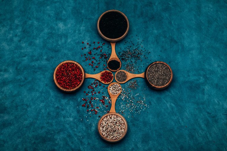 Wooden spoons of seeds, grains and legumes on a blue surface